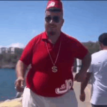 a man wearing a red shirt and a dollar sign necklace .