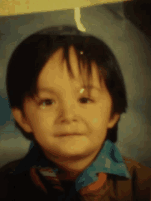 a close up of a child 's face with a blue shirt and brown jacket