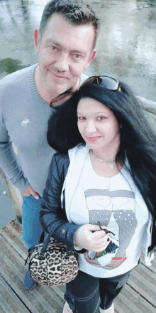 a man and a woman pose for a picture on a wooden bridge