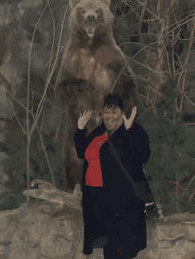 a woman stands in front of a large stuffed bear