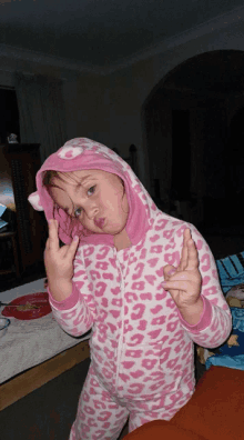 a little girl wearing a pink and white leopard print pajama set making a funny face