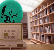 a green ball with a face on top of a computer in a library .