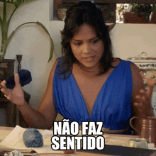 a woman in a blue dress is sitting at a table with the words " não faz sentido " above her