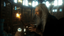 a man with long white hair and a beard holds a magic wand