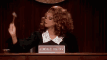 a woman in a judge 's robe is holding a gavel in a courtroom and giving the middle finger .