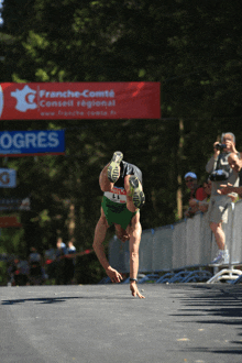 a runner is doing a handstand in front of a french-comte banner