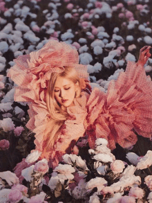 a woman in a pink dress surrounded by flowers