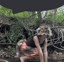 a woman is wearing a cat mask and kneeling in the woods .