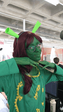 a woman in a shrek costume holds a phone