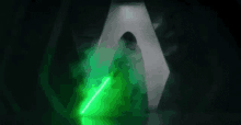 a man is holding a green lightsaber in a dark room .