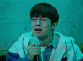 a young man is singing into a microphone and crying