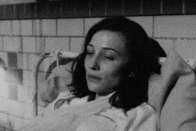 a black and white photo of a woman laying in a hospital bed with her eyes closed