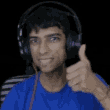 a man wearing headphones is giving a thumbs up sign