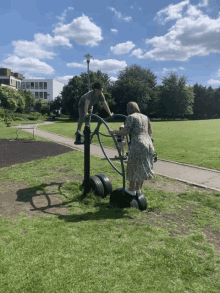 a man and a woman are playing on a exercise machine in the park