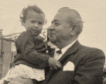 a man in a suit and tie is holding a little girl in his arms