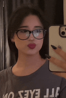 a woman wearing glasses takes a selfie in a mirror