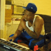 a man is playing a m-audio keyboard while wearing a blue hat