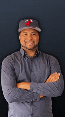 a man with his arms crossed wearing a hat with the miami heat logo on it