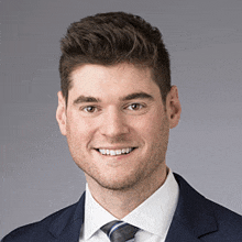 a man wearing a suit and tie is smiling for the camera .