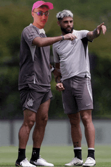 a man in a pink hat stands next to a man in a grey shirt