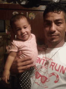 a man is holding a baby wearing a shirt that says ' enter run ' on it