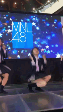 a group of girls are dancing in front of a screen that says mnl48