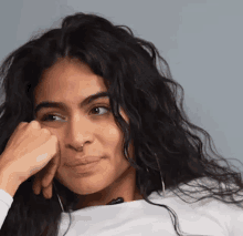 a woman with long curly hair and a nose ring is looking at the camera .