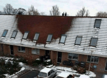 a row of houses with snow on the roofs and cars parked in front