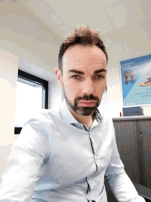 a man with a beard is sitting at a desk in front of a poster that says " l' avenir " on it