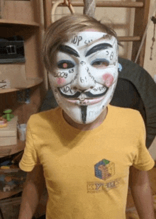 a boy wearing a anonymous mask and a yellow t-shirt