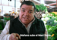 a man standing in front of a bunch of vegetables with the words " mañana sube el mani reina " above him