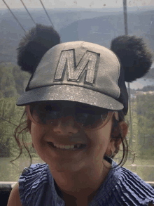 a girl wearing sunglasses and a hat with the letter m on it