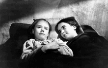 a black and white photo of two young girls laying on a bed