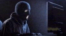 a man in a ski mask is looking at a computer screen