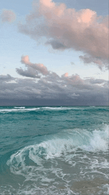 waves crashing on a beach with a cloudy sky