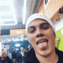 a young man wearing a beanie is sticking out his tongue .