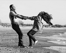 a man is holding a woman in his arms on the beach .