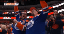 two men in edmonton oilers jerseys celebrate a goal during a hockey game