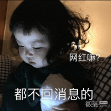 a little girl is holding a stuffed animal with chinese writing on it