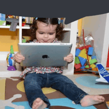 a little girl sitting on the floor using an apple tablet