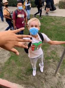 a boy wearing a mask and a shirt that says spongebob is giving a peace sign