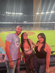 a man wearing a blue jays shirt stands with two women