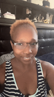 a woman wearing glasses and a striped tank top smiles at the camera