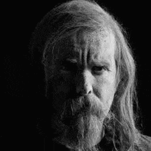 a black and white photo of an old man with long hair and a beard .