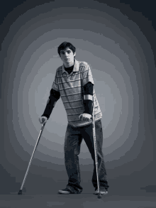 a young man is using crutches to walk on a gray background