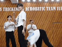 a group of young men are practicing acrobatics in front of a sign that says ' tricking acrobatic team 11 '