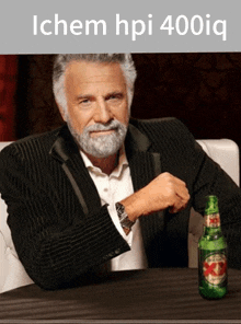 a man in a suit sits at a table with a bottle of beer