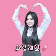 a girl making a heart shape with her hands with a pink background and hearts behind her