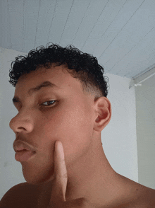 a shirtless young man with curly hair giving a thumbs up