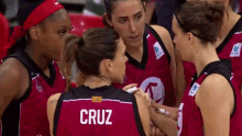 a group of female basketball players are huddled together and one of them has the name cruz on the back of her jersey .